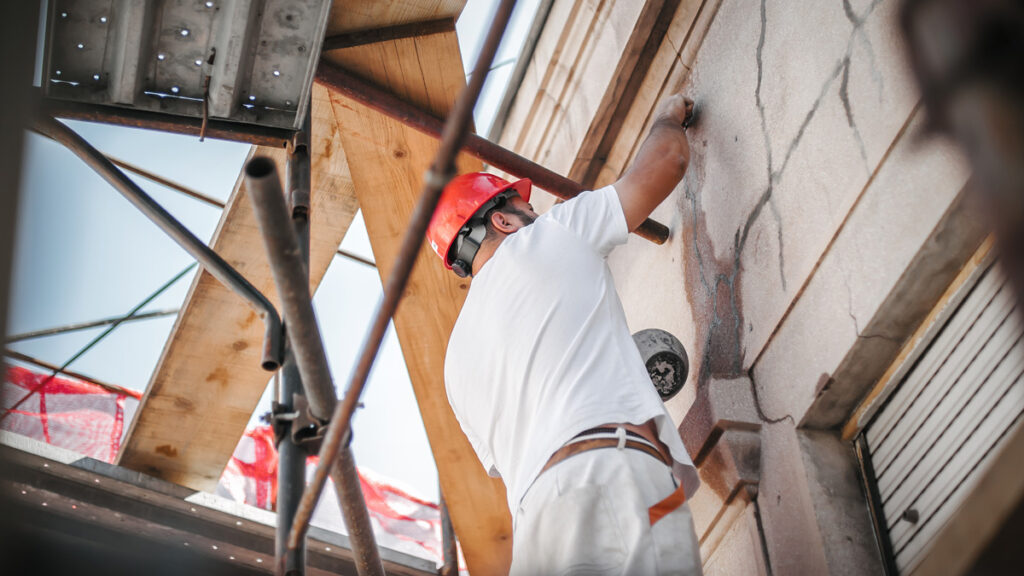 Artisan façadier de l'équipe Jentellet en cours de travaux de réparation de façade fissurée